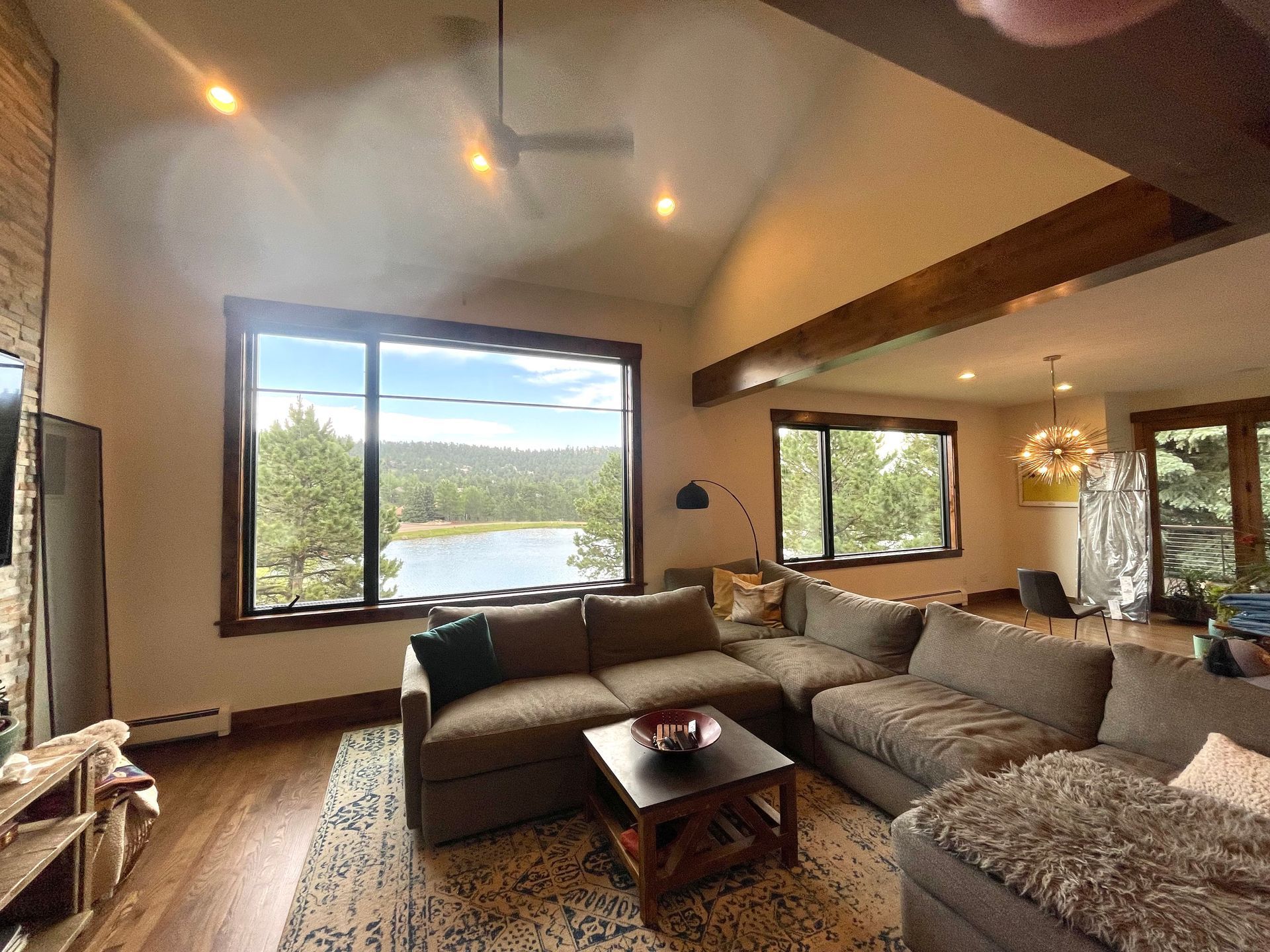 Living room with a sectional sofa, coffee table, and large windows overlooking a lake.