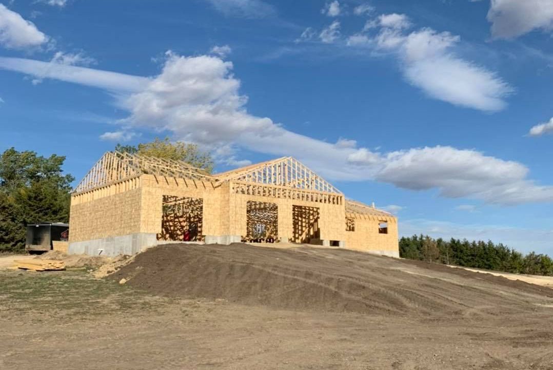 A large wooden house is being built on top of a dirt hill.