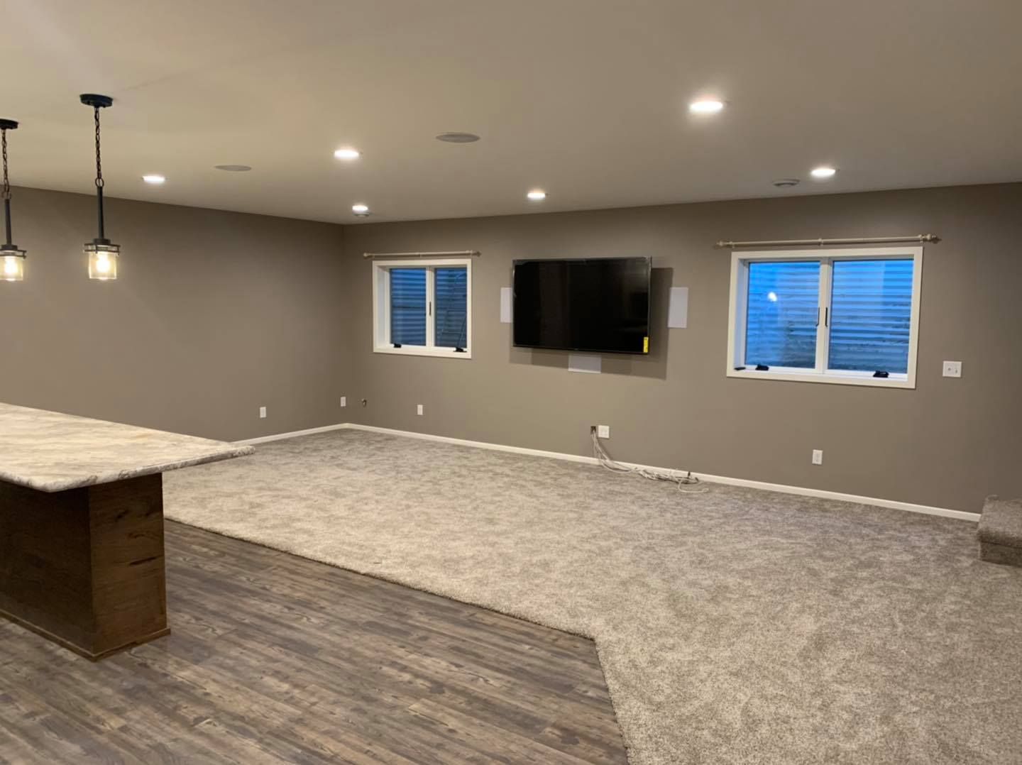 A large empty room with a flat screen tv on the wall.