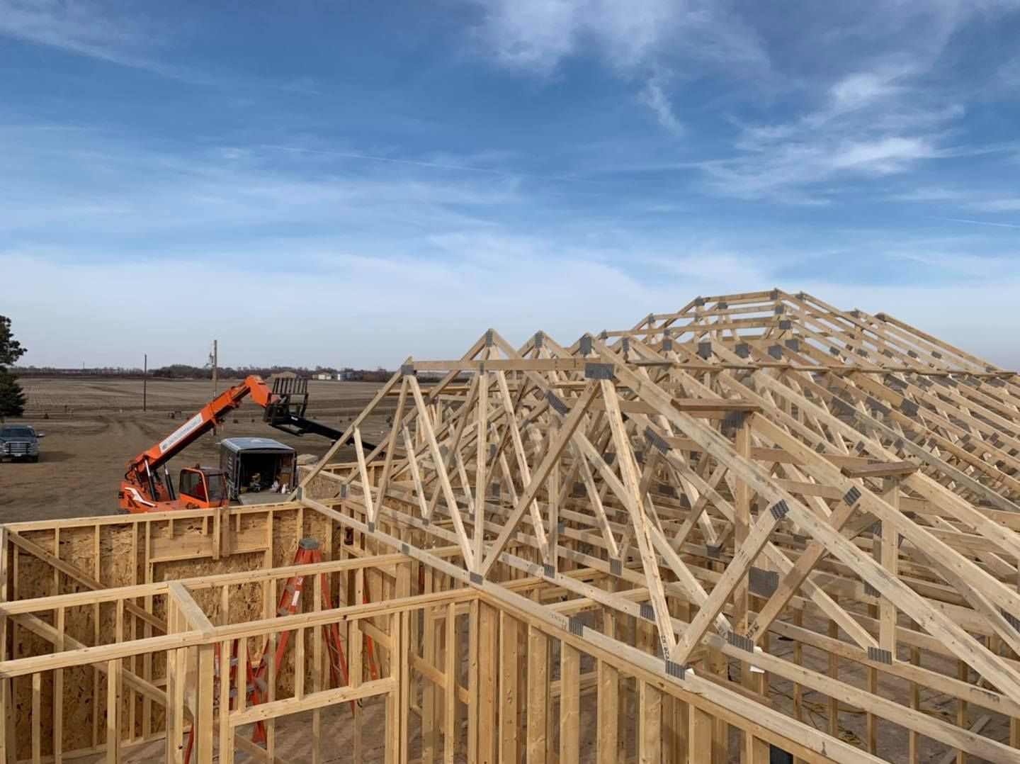 A large wooden structure is being built in a field.