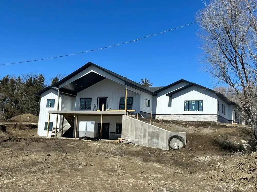 A large white house is sitting on top of a dirt hill.