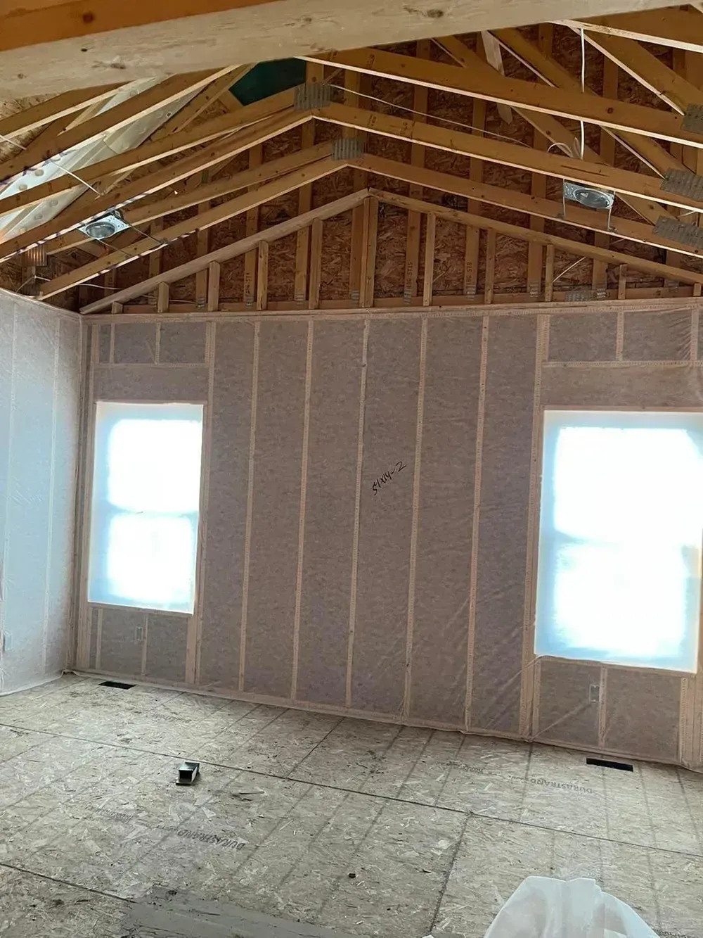 A room in a house under construction with a lot of windows.
