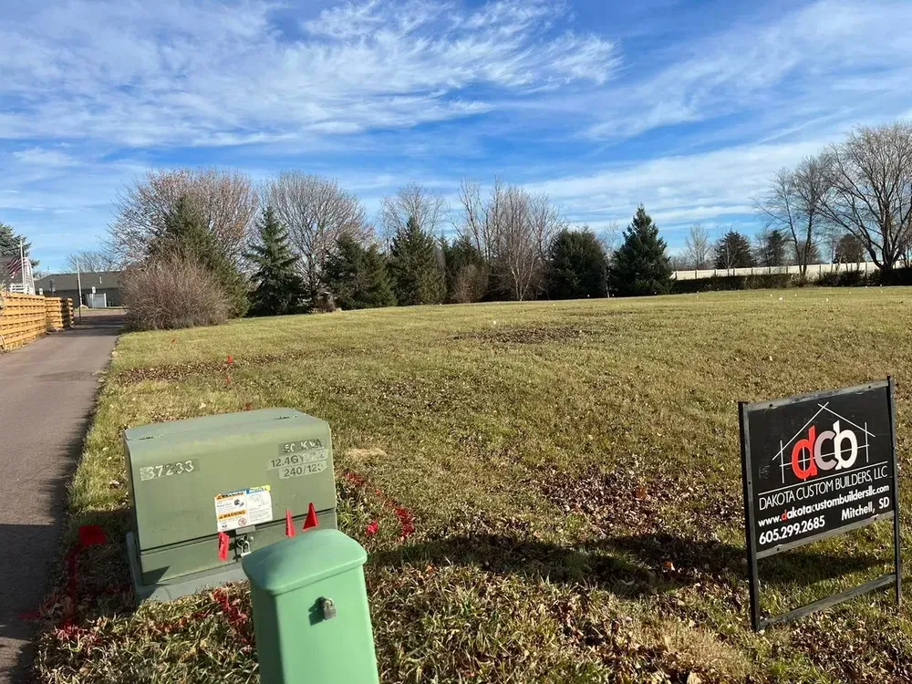 A large grassy field with a for sale sign in the middle of it.