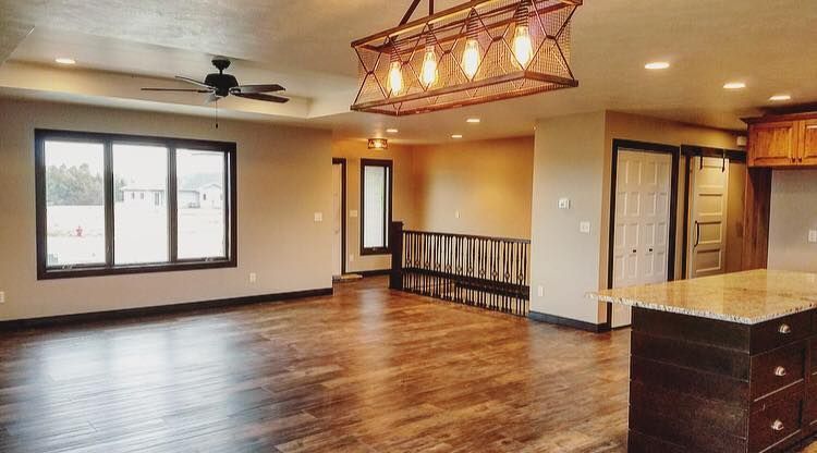A large empty room with hardwood floors and a ceiling fan.