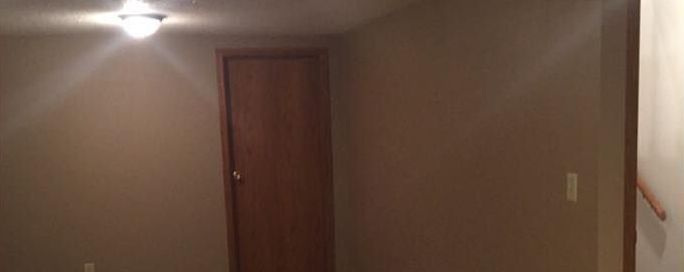 A hallway with a door and a light on the ceiling.