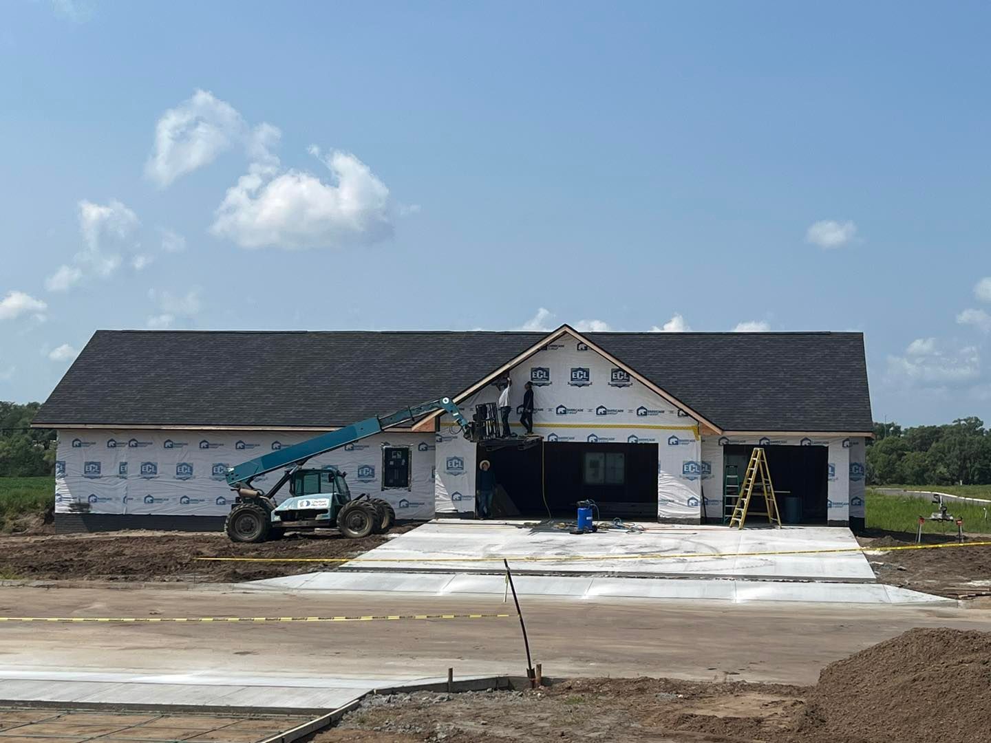 A house is being built with a concrete driveway in front of it.