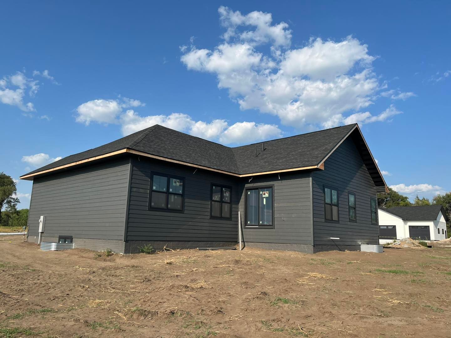 A black house with a black roof is sitting on top of a dirt field.