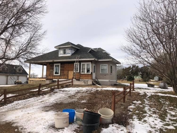 A house with a fence and buckets in front of it in the snow.