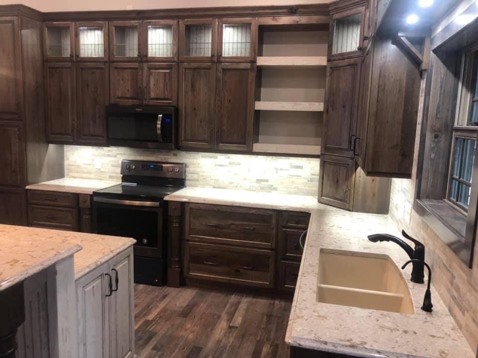 A kitchen with a sink , stove , microwave and cabinets.