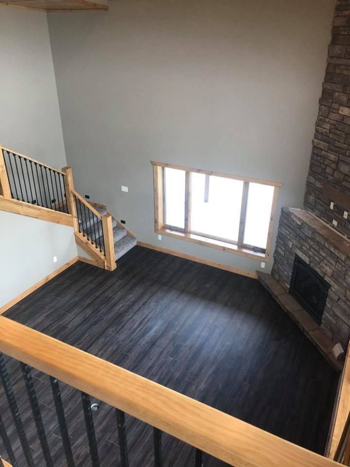 An empty living room with a fireplace and stairs.