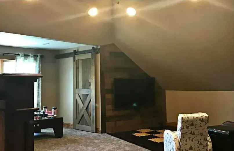A living room with a sliding barn door and a flat screen tv.