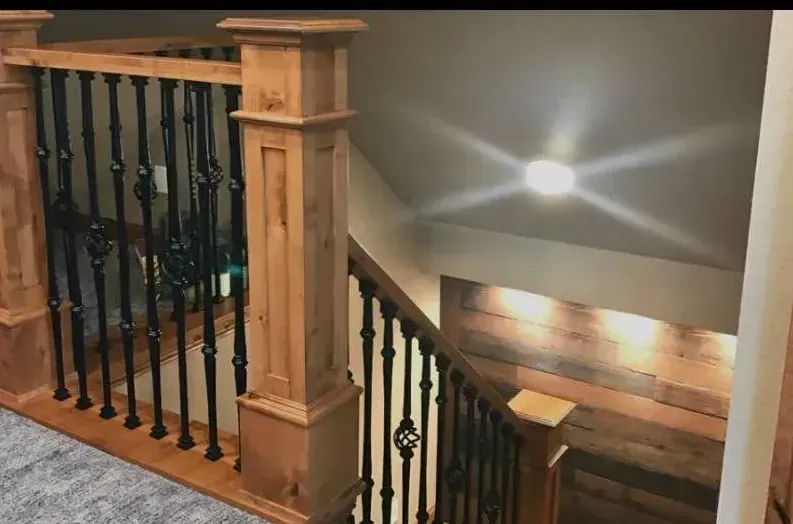 A wooden staircase with a black railing and a light on the ceiling.