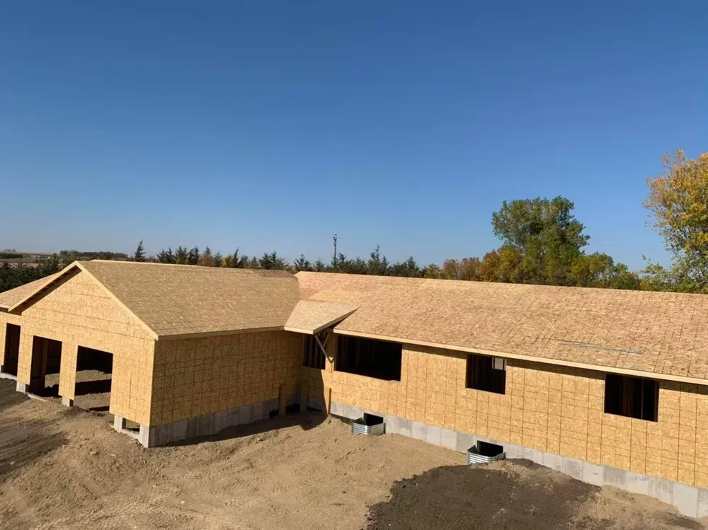 A large house is being built in the middle of a dirt field.