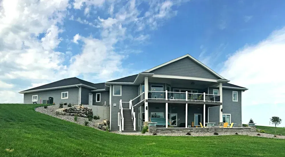 A large house is sitting on top of a lush green hill.