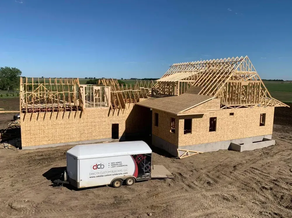 A trailer is parked in front of a house under construction.