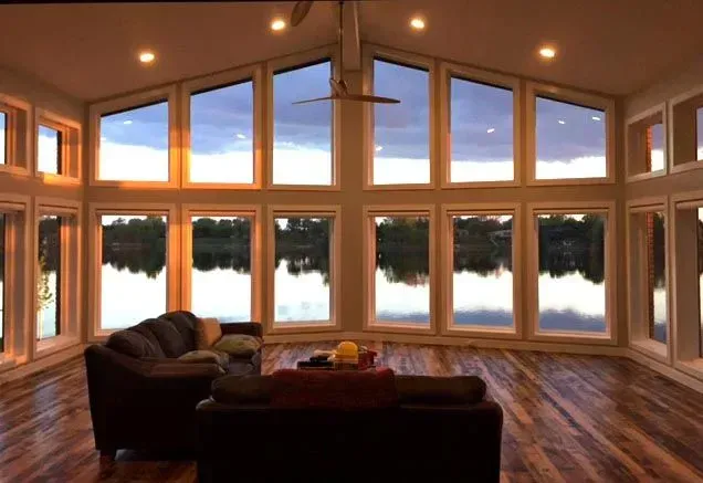 A living room with a lot of windows overlooking a lake