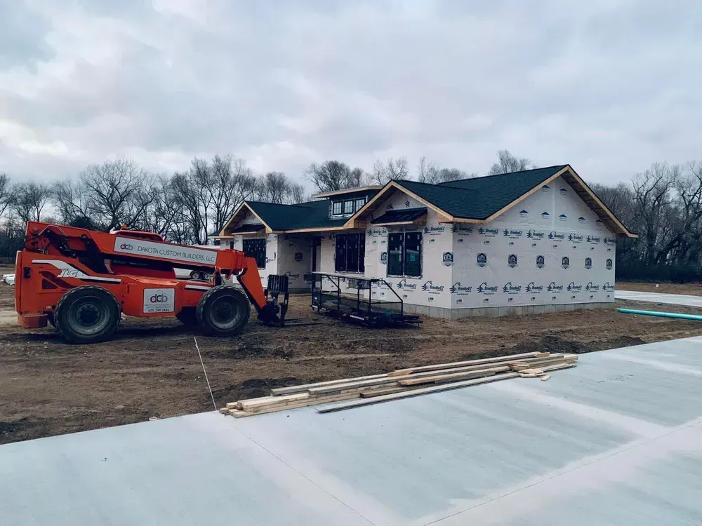 A forklift is parked in front of a house under construction.