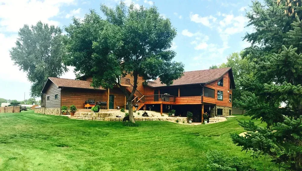 A large log cabin is sitting in the middle of a lush green field.