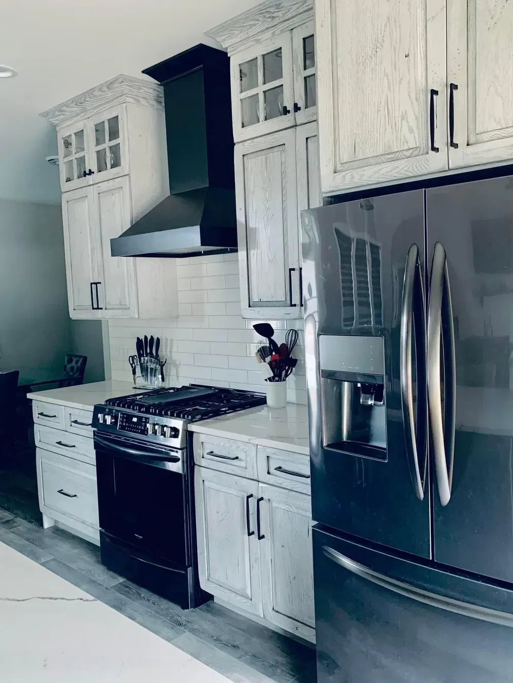 A kitchen with white cabinets , stainless steel appliances , a stove and a refrigerator.