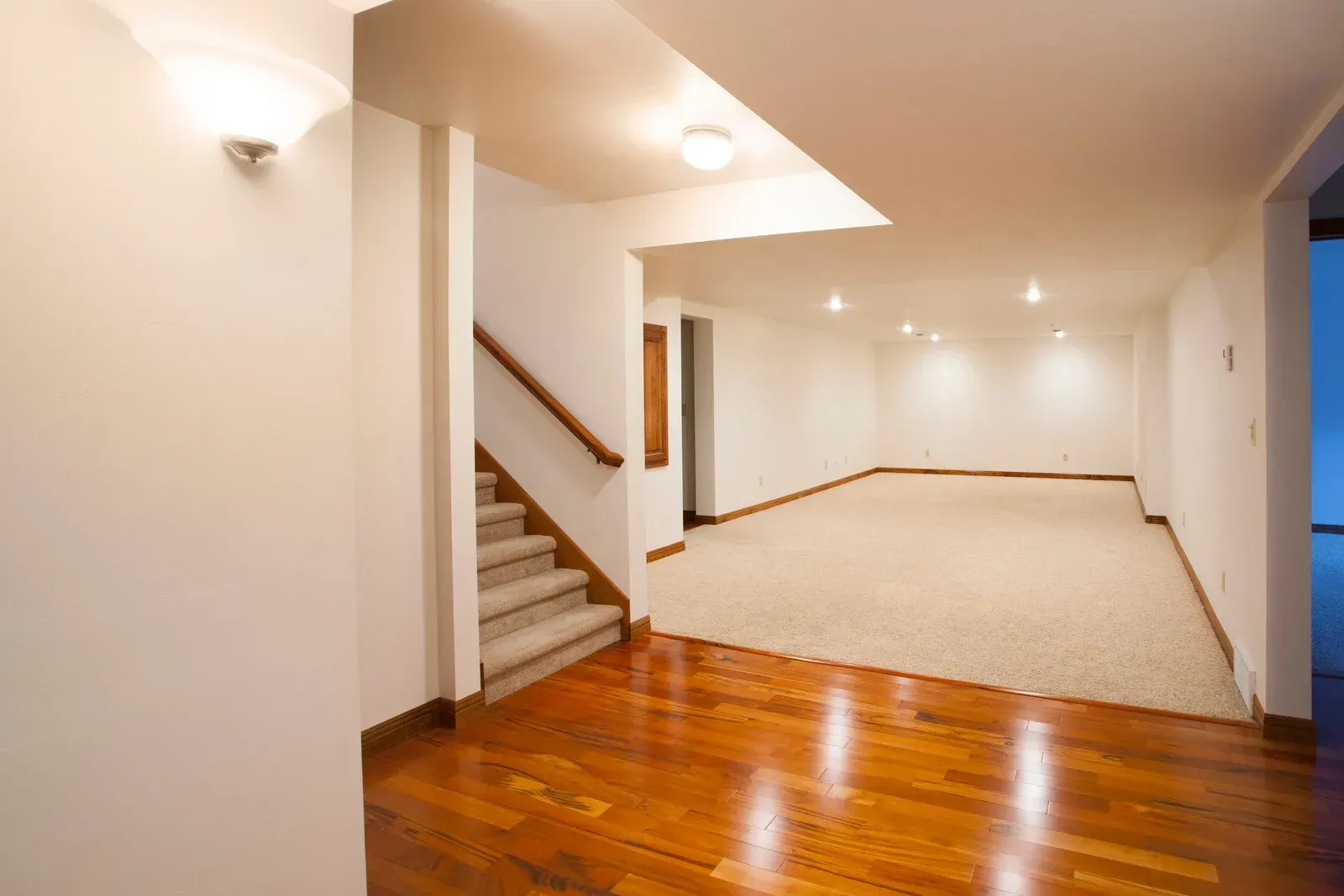 An empty basement with hardwood floors and stairs