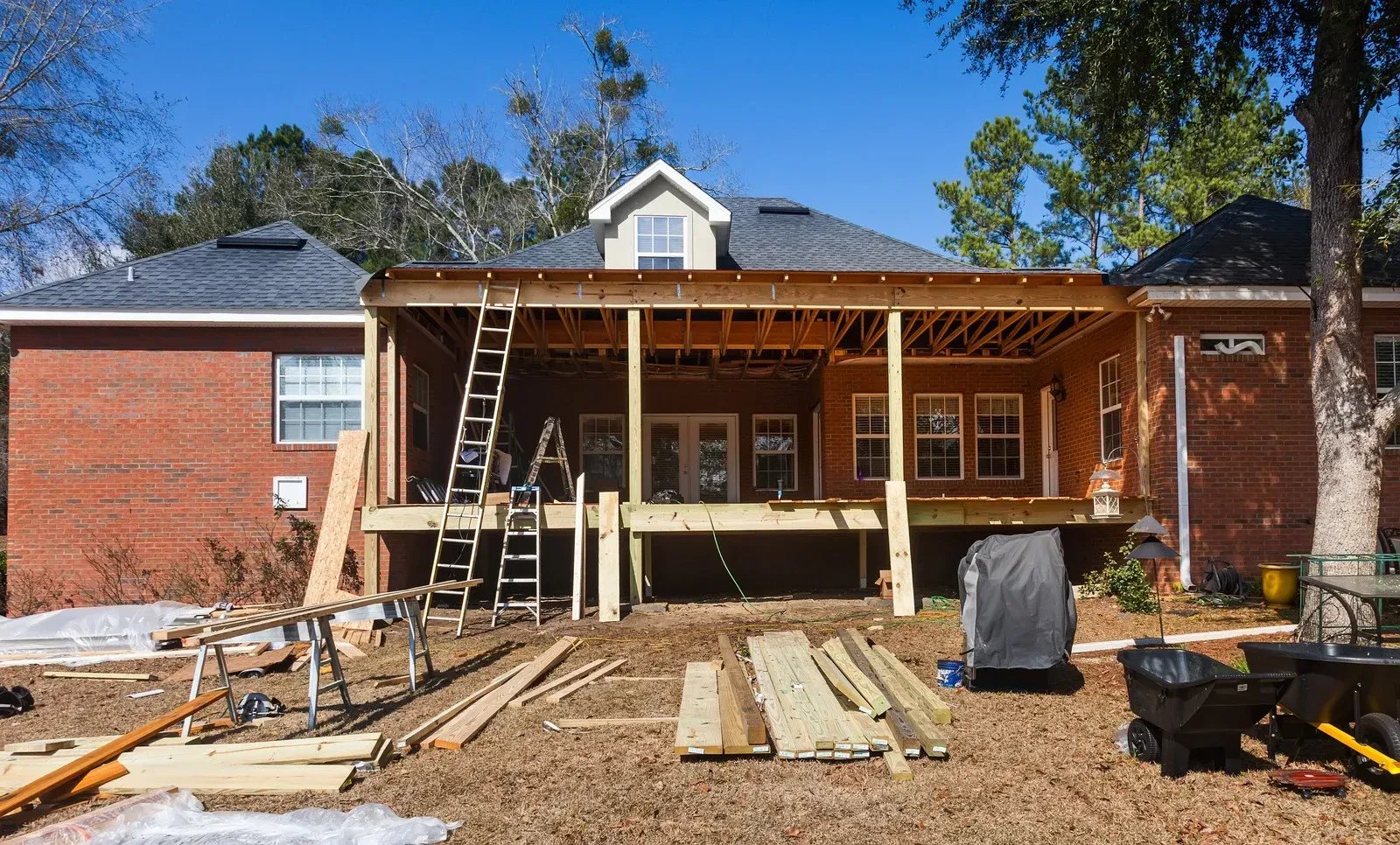 A brick house is being remodeled with a wooden porch.