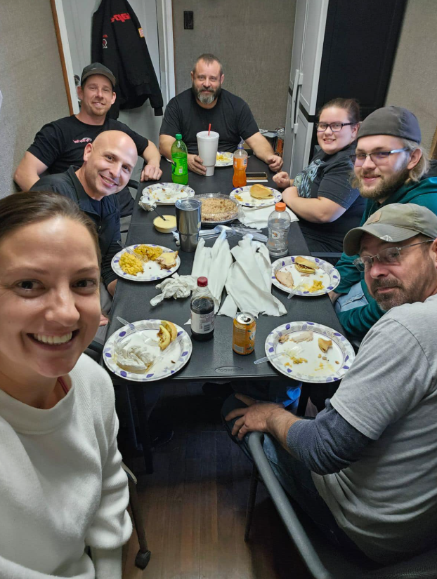 A group of people are sitting around a table with plates of food.