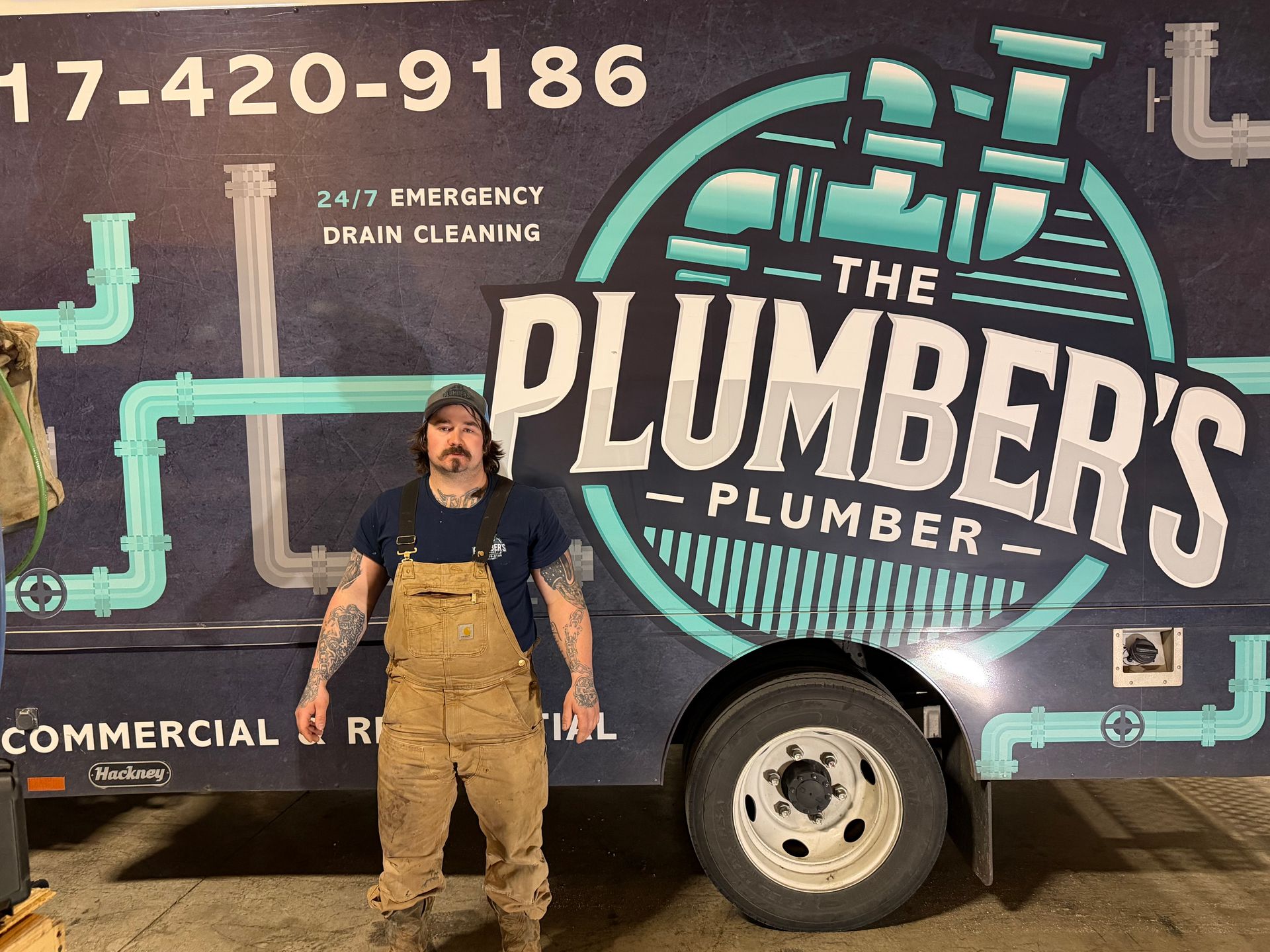 Man in overalls stands by a plumbing truck with logo 
