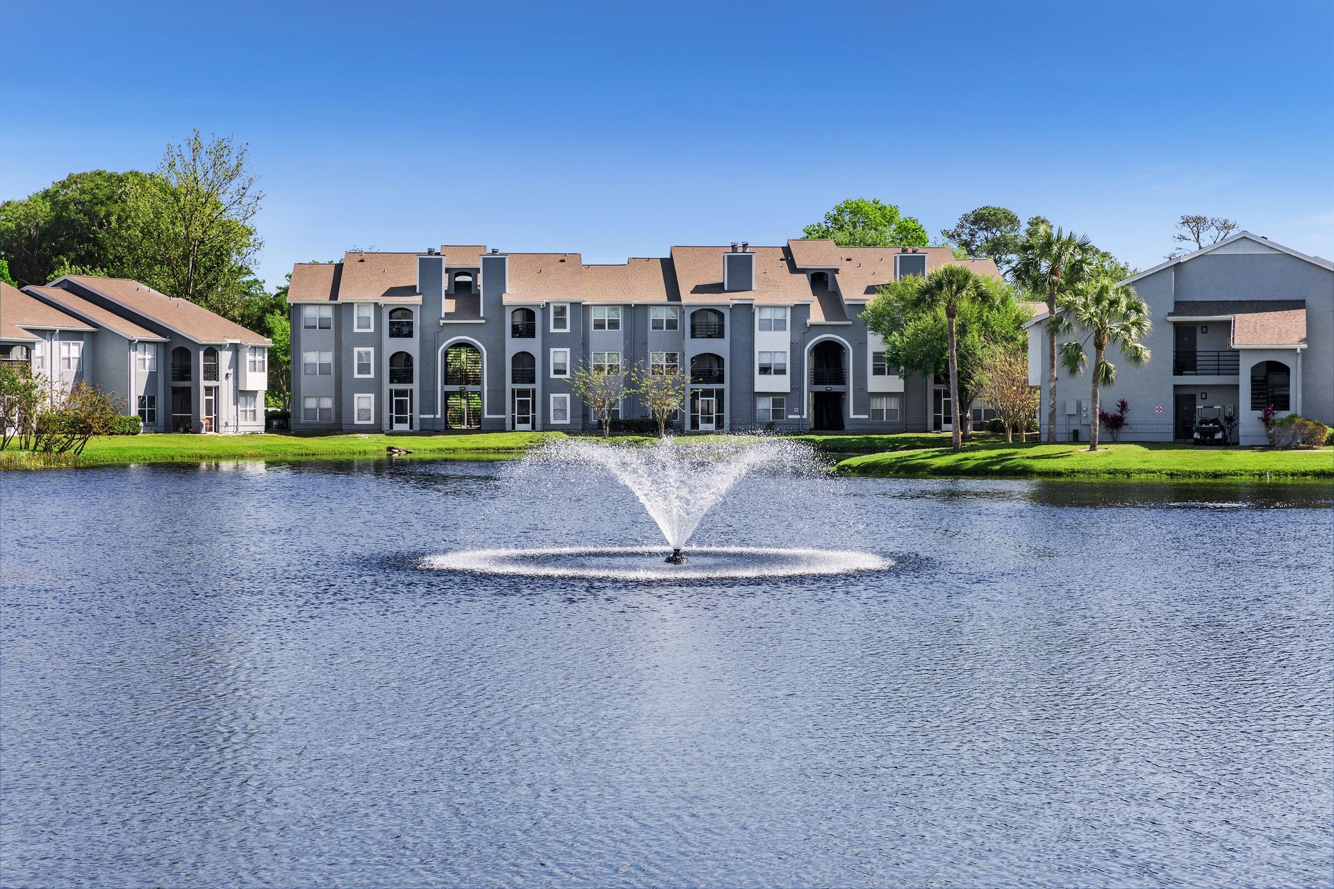 A fountain in the middle of a lake in front of a building