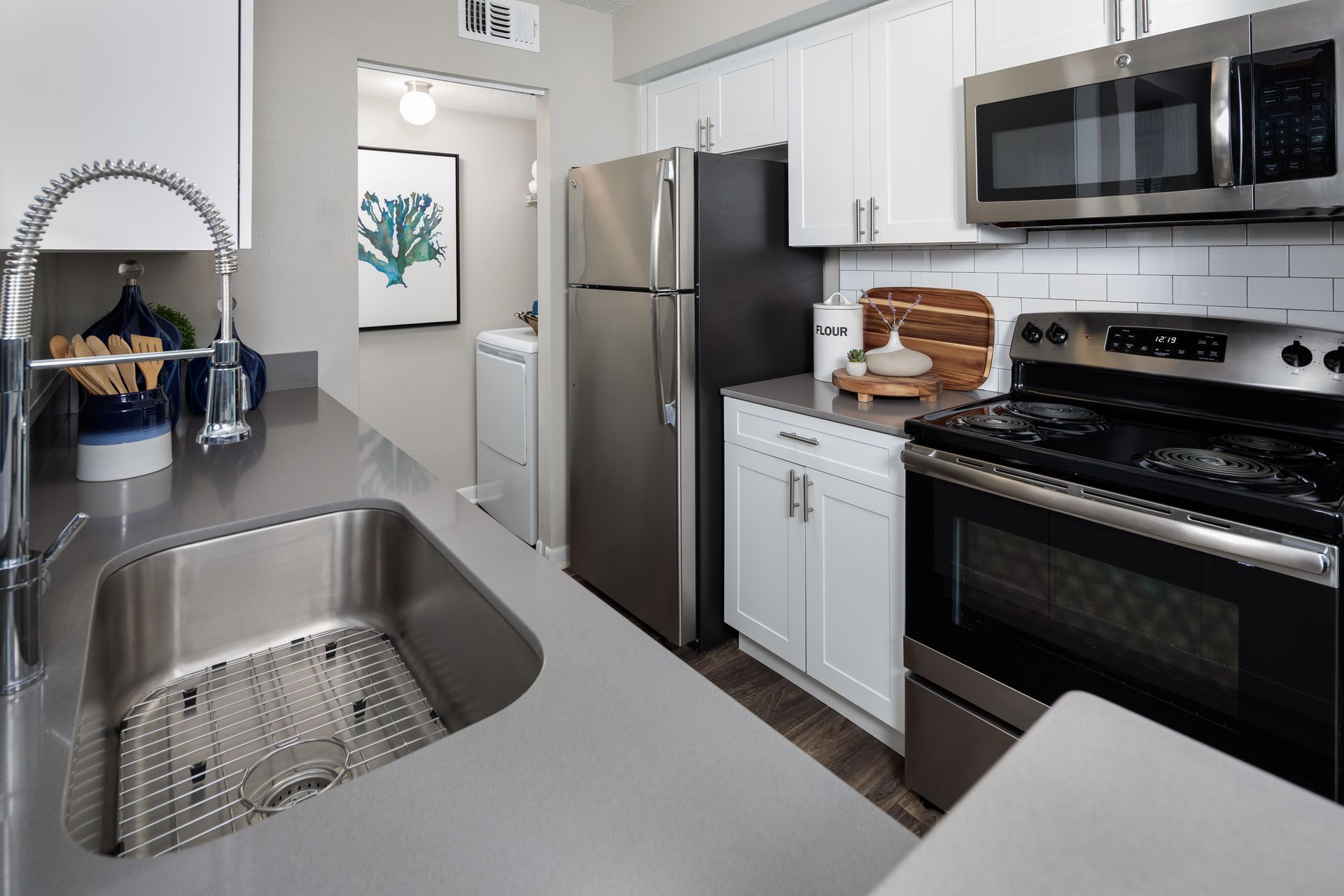 A kitchen with a sink , stove , refrigerator and microwave.