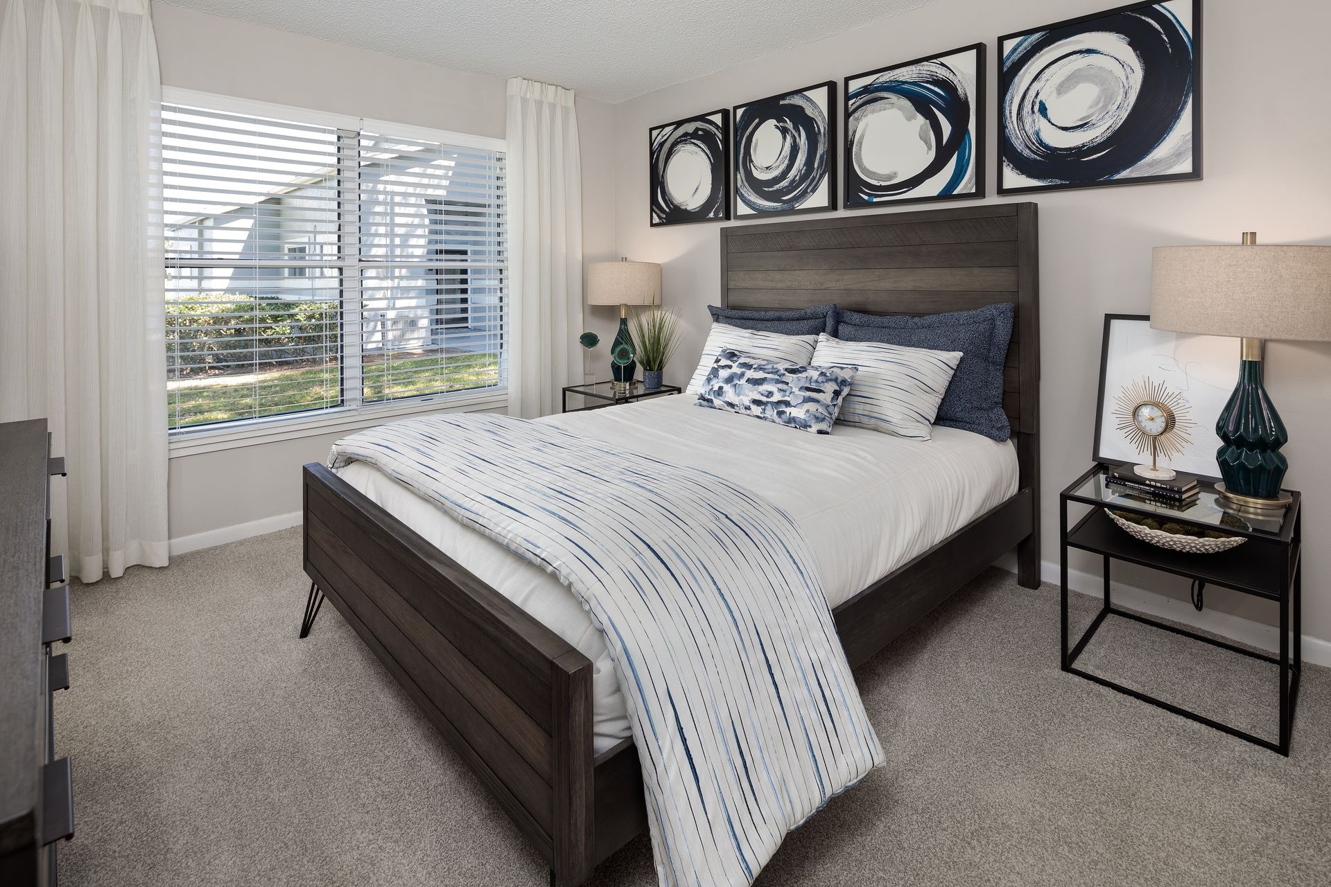 A bedroom with a bed , nightstand , lamps and a window.