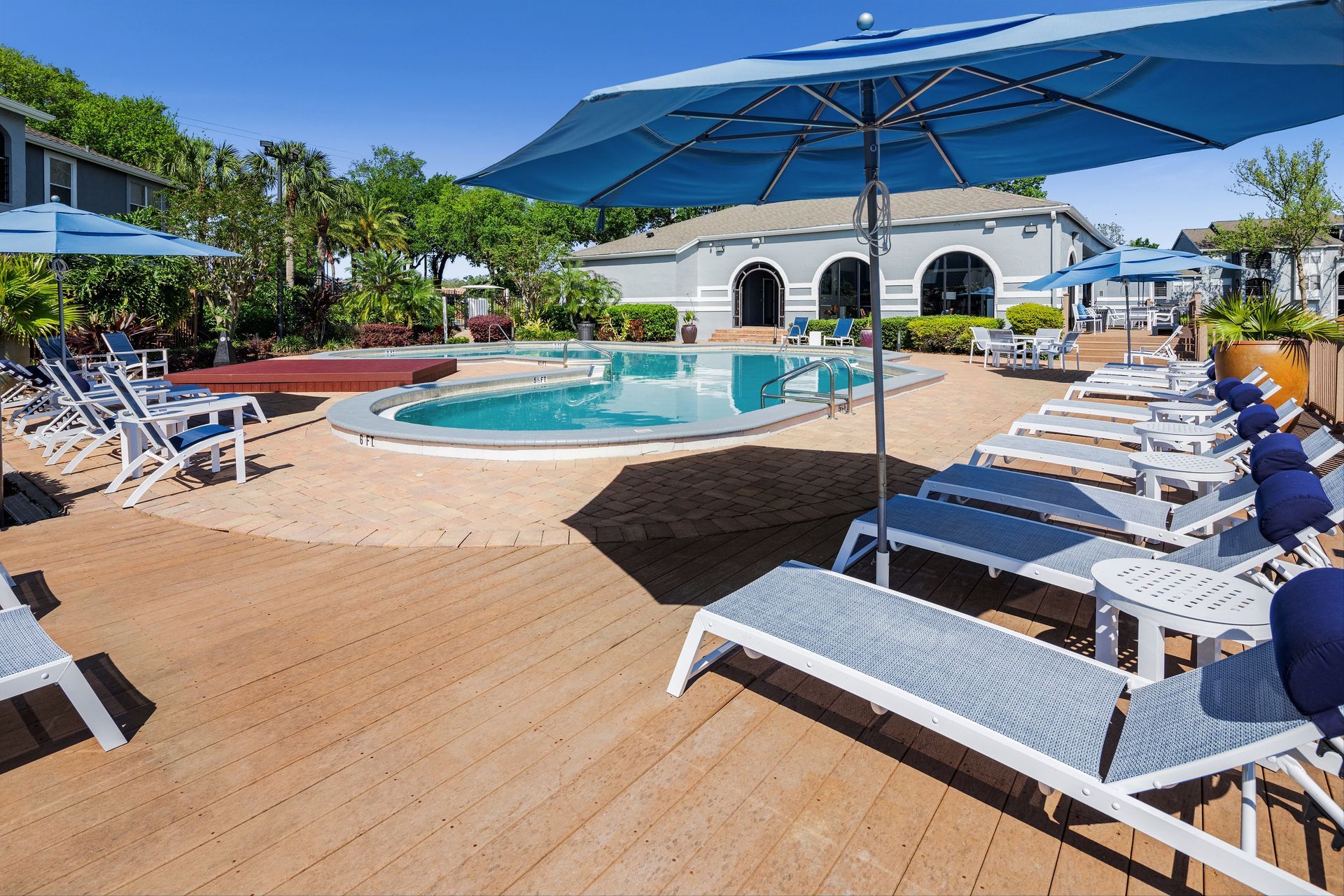 A swimming pool with umbrellas and lounge chairs around it.