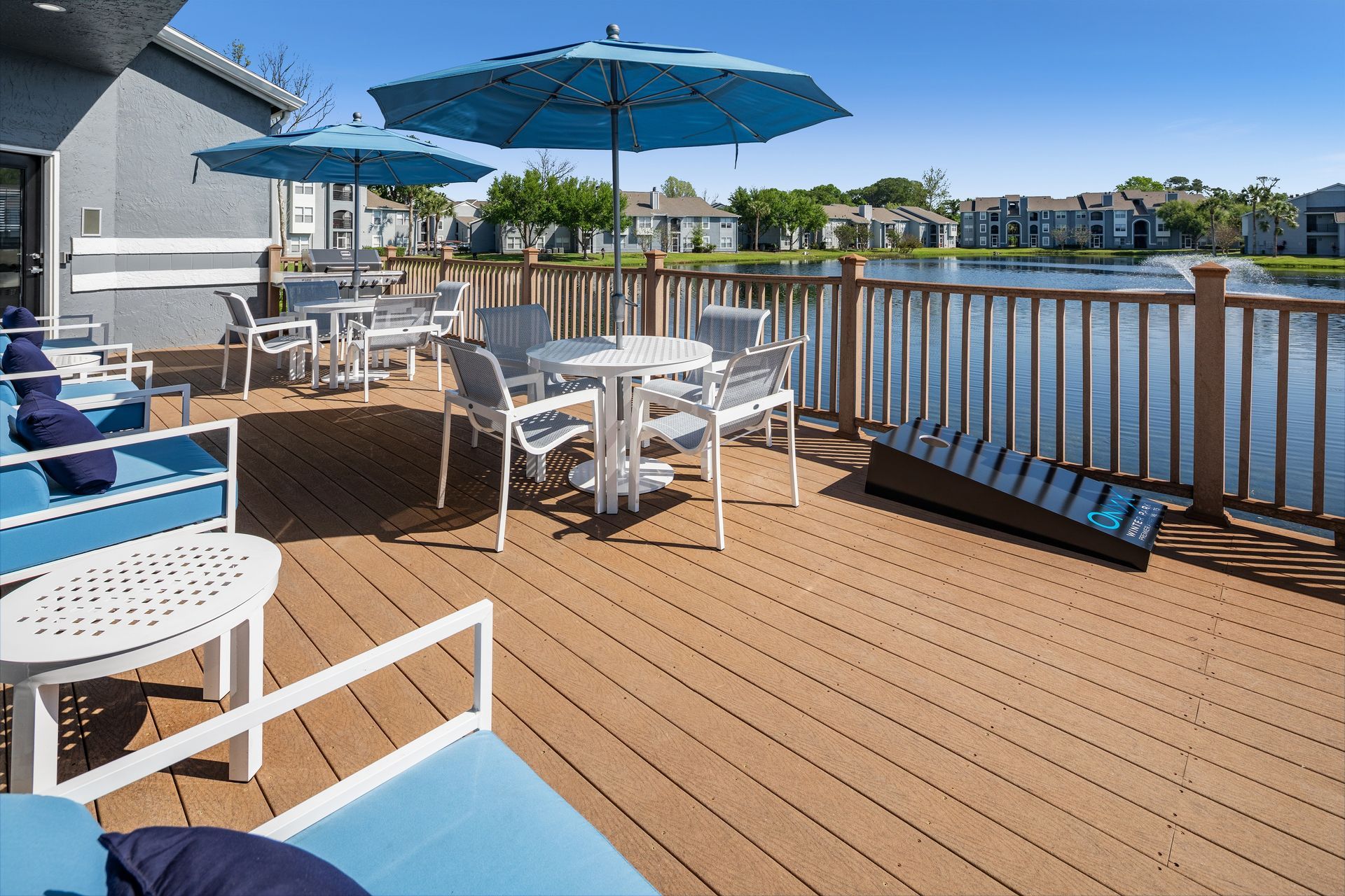 A deck with tables and chairs and umbrellas overlooking a lake.