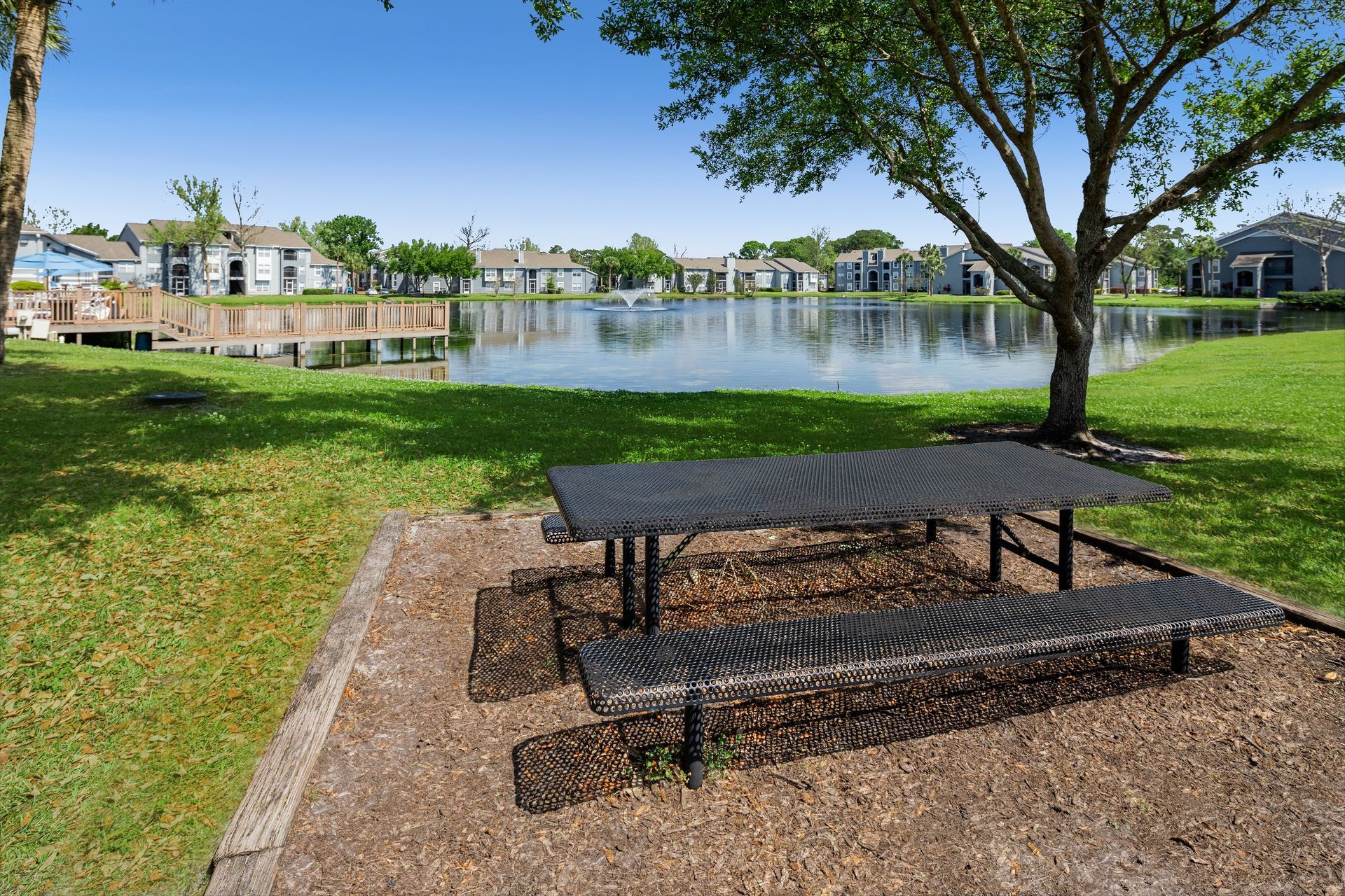 A picnic table in a park next to a lake.