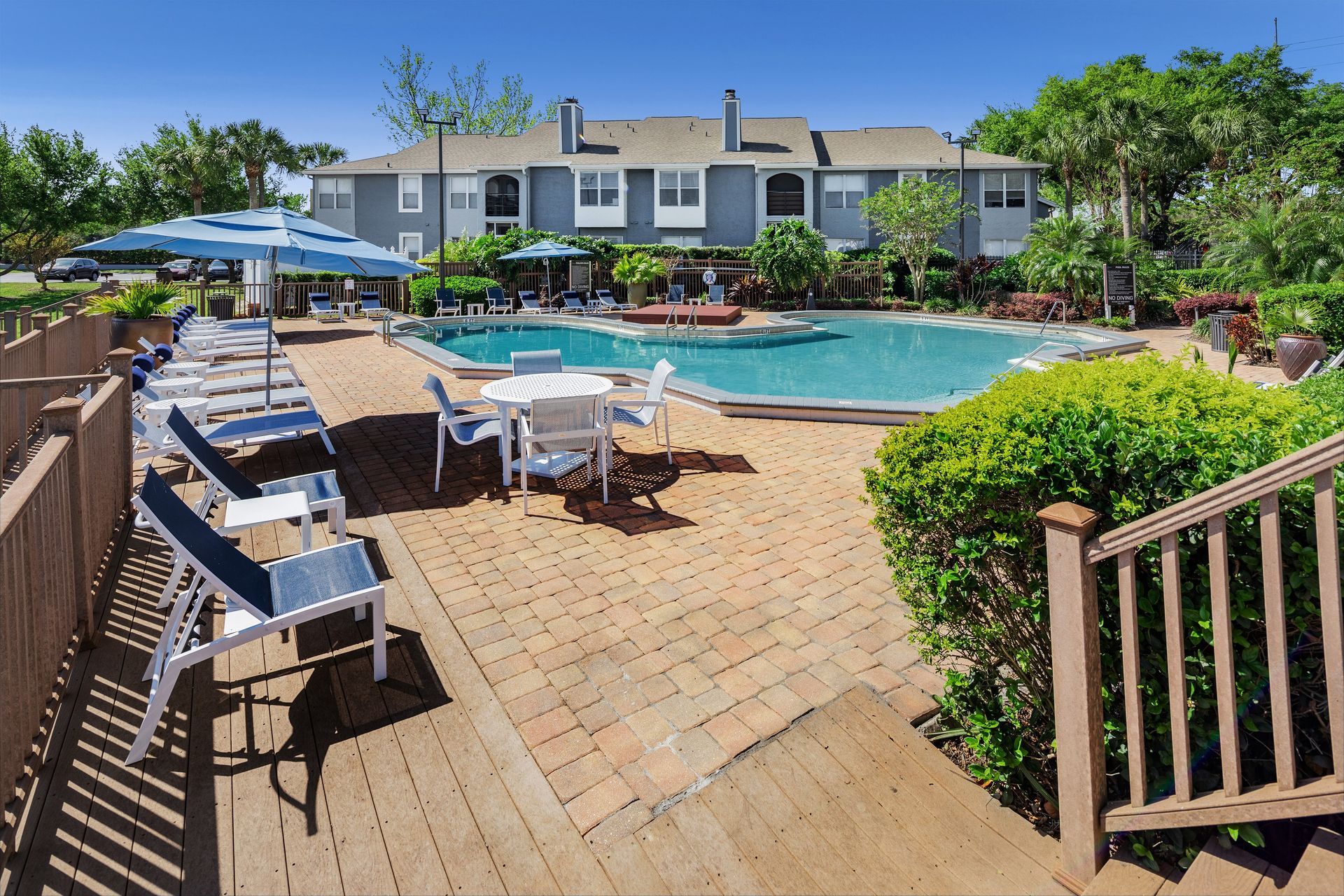 A large swimming pool is surrounded by chairs and tables