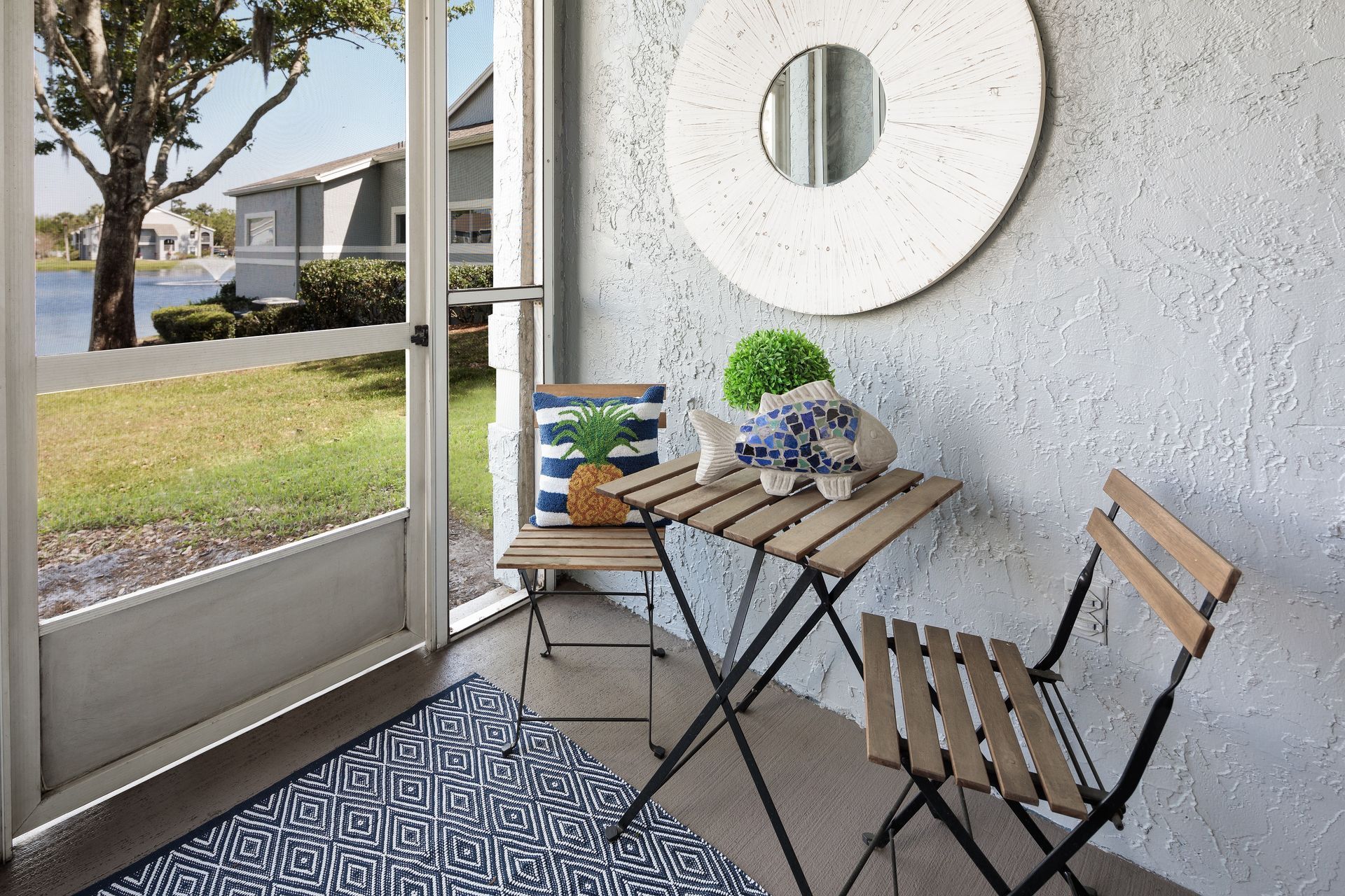 A porch with a table and chairs and a mirror.