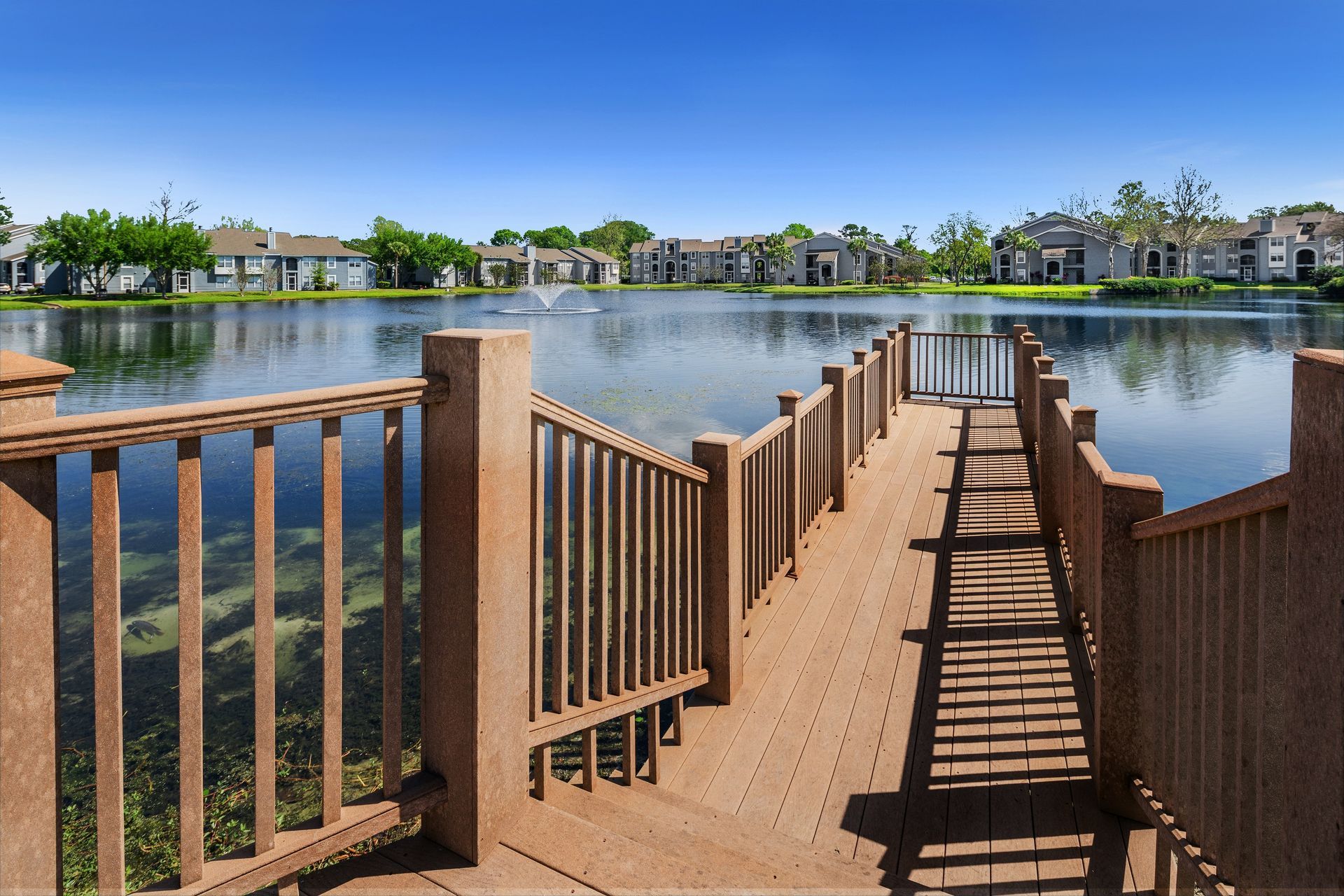 A wooden dock leading to a lake with houses in the background