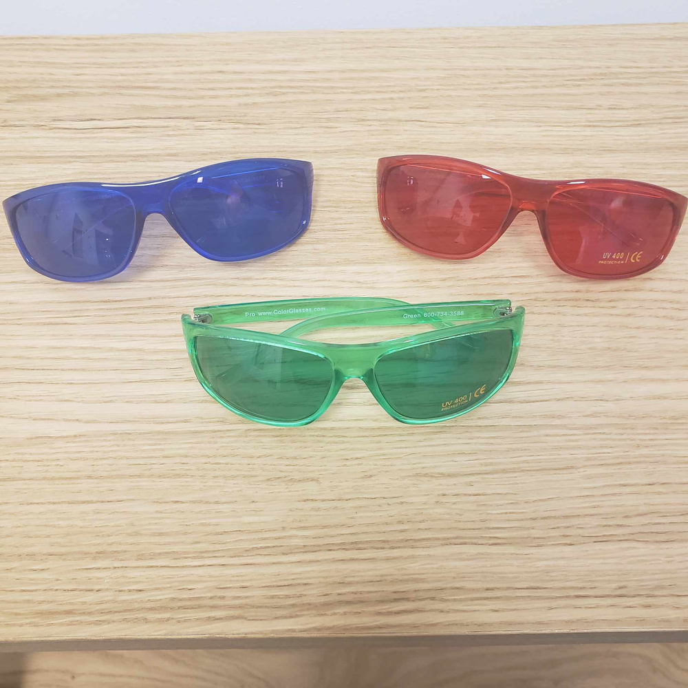 Three pairs of sunglasses are sitting on a wooden table.