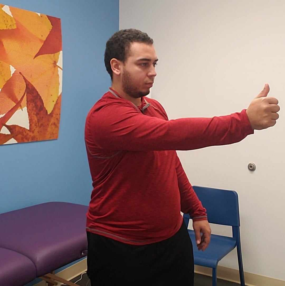 A man in a red shirt is giving a thumbs up