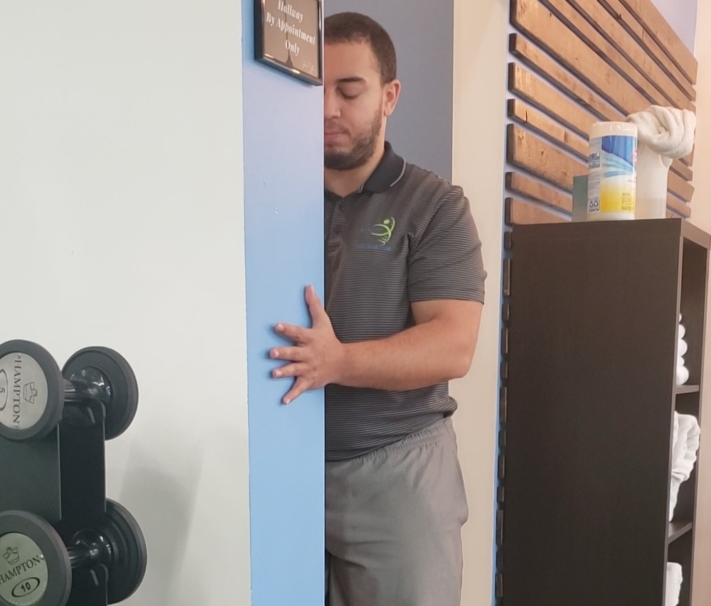 A man is leaning against a wall in a gym.