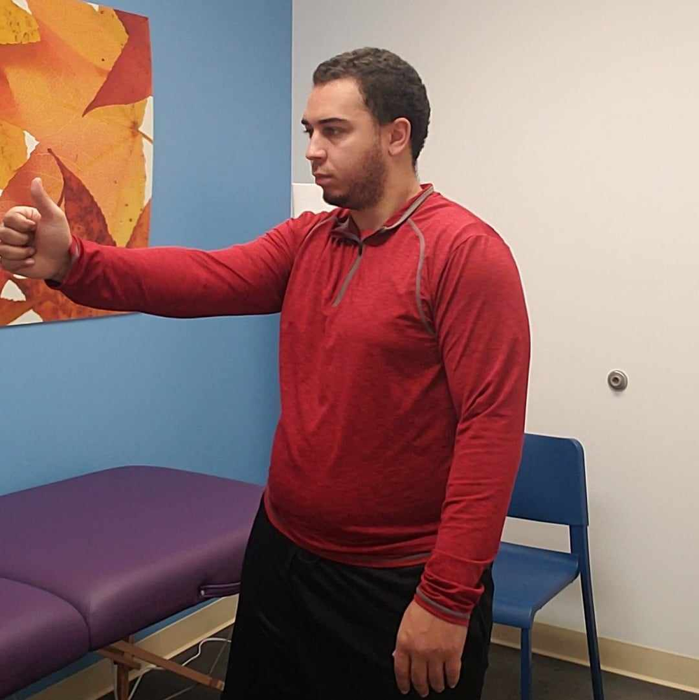 A man in a red shirt is giving a thumbs up