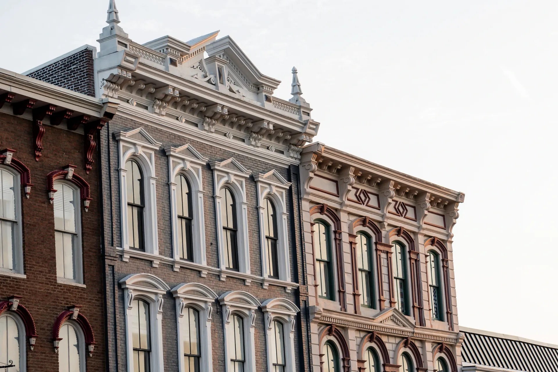 Row of ornate, historic buildings with detailed white and brown facades, under a light sky.