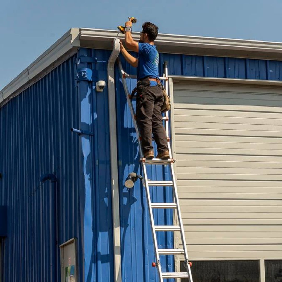 A man is standing on a ladder on the side of a building.