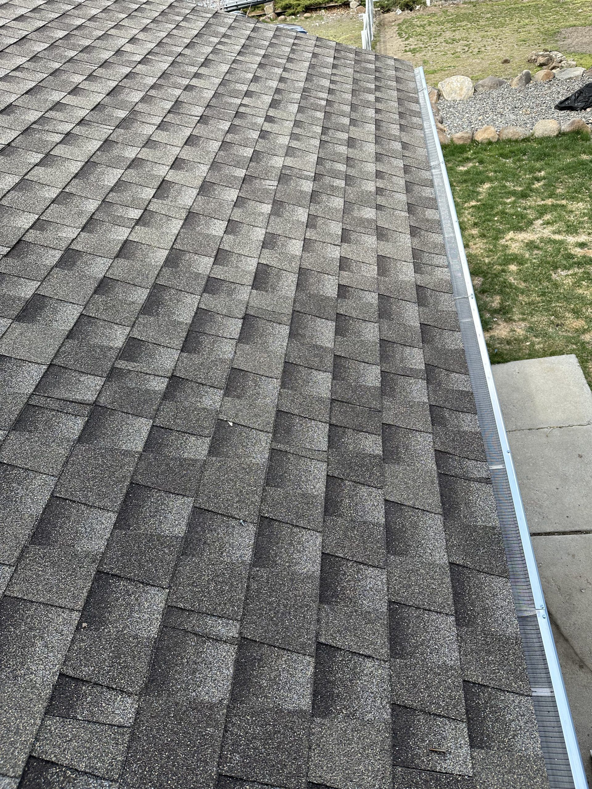 A close up of a roof with shingles and a gutter.
