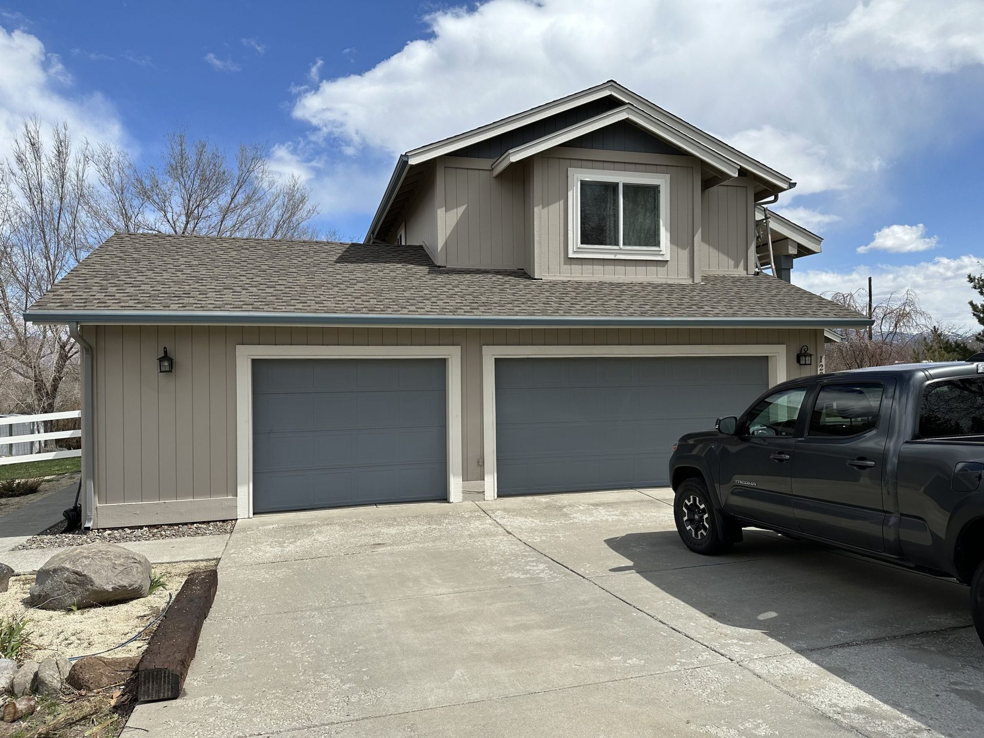 A truck is parked in front of a house with two garage doors