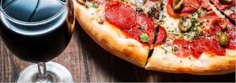 A close-up of a glass of red wine and a slice of pizza, showing the harmony between pizza and wine flavors.