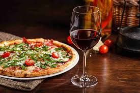 Wine glasses beside a fresh pizza, showcasing the ideal wine pairing for different pizza varieties.