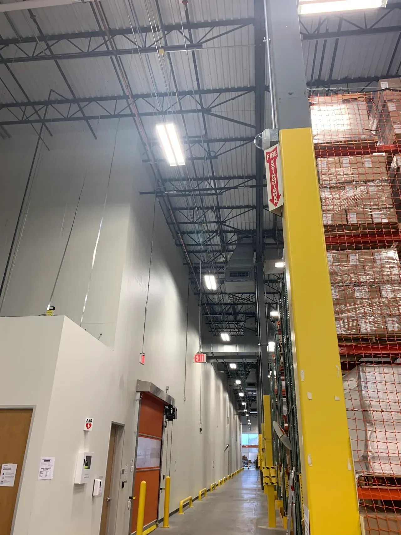 Warehouse interior with tall racks of goods, aisle, and fire safety details.