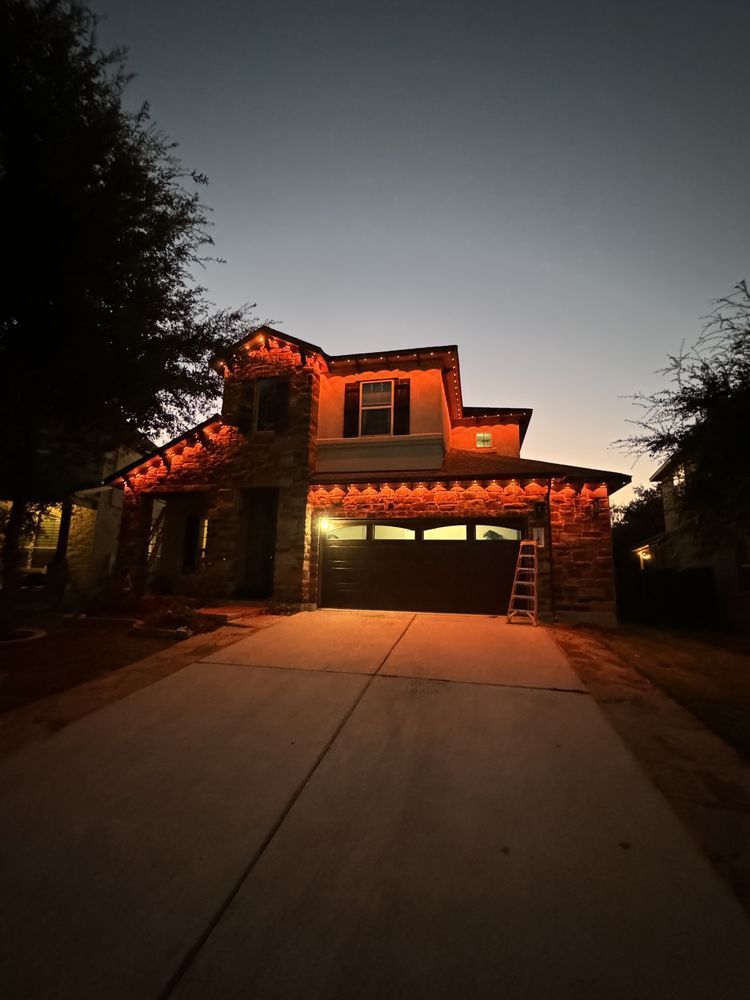 House lit with orange Christmas lights at dusk.