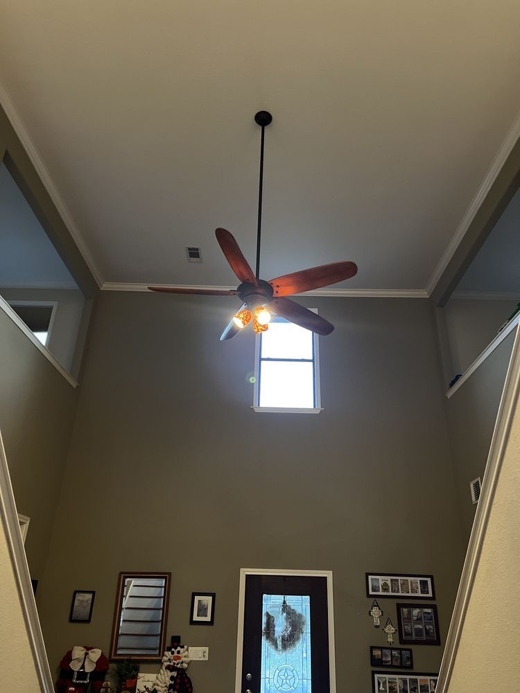 A two-story entryway with a ceiling fan, small window, and a closed front door.