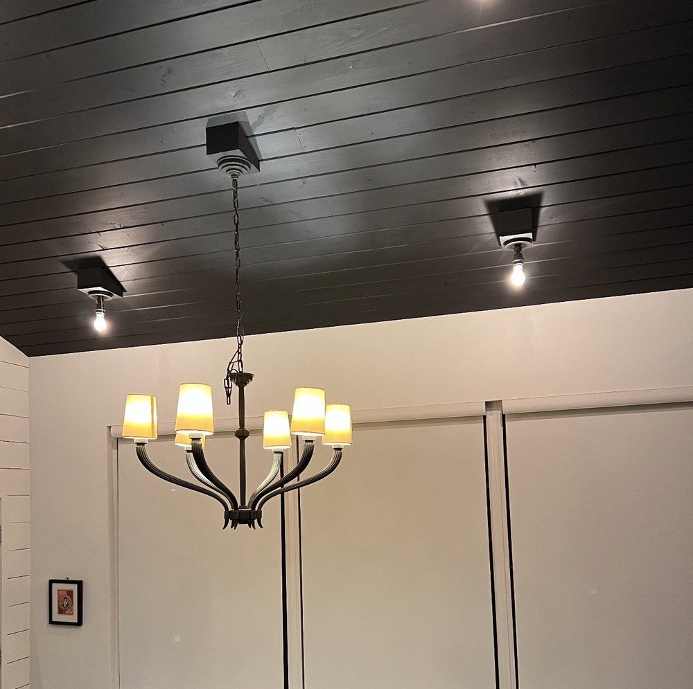 Black ceiling with track lighting and chandelier over white walls and sliding doors.